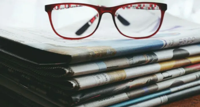 red-eyeglasses-on-a-stack-of-newspapers.jpg.webp.webp