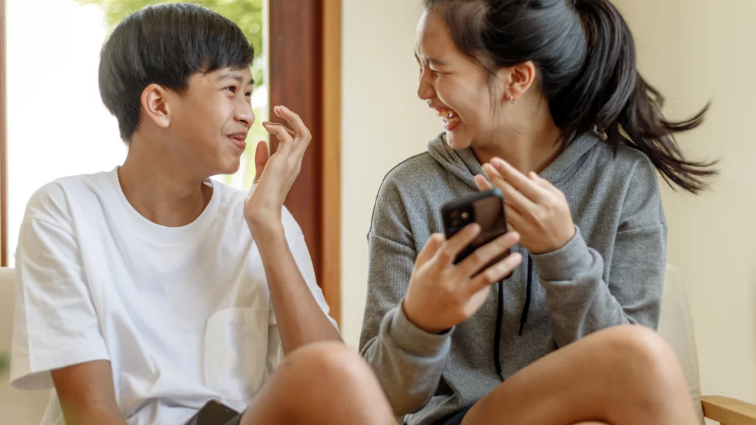 MSFT-Two-teenagers-having-a-good-time-while-using-GroupMe-on-a-mobile-phone.webp